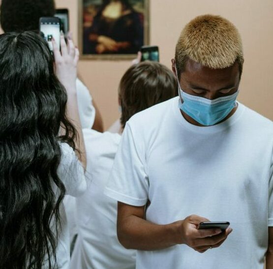 Group Of People Looking At A Painting Of Mona Lisa With Face Mask and holding mobile phones